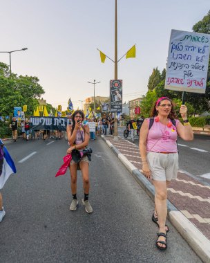 Hayfa, İsrail - 23 Ağustos 2025: Çeşitli tabelaları ve bayrakları olan insanlar, savaşın sona ermesi, rehine anlaşmasının tamamlanması ve yeni seçimler için düzenlenen protesto mitingine katıldılar. Hayfa, İsrail