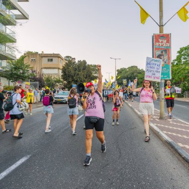 Hayfa, İsrail - 23 Ağustos 2025: Çeşitli tabelaları ve bayrakları olan insanlar, savaşın sona ermesi, rehine anlaşmasının tamamlanması ve yeni seçimler için düzenlenen protesto mitingine katıldılar. Hayfa, İsrail