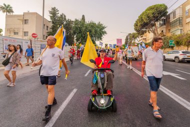Hayfa, İsrail - 23 Ağustos 2025: Çeşitli tabelaları ve bayrakları olan insanlar, savaşın sona ermesi, rehine anlaşmasının tamamlanması ve yeni seçimler için düzenlenen protesto mitingine katıldılar. Hayfa, İsrail