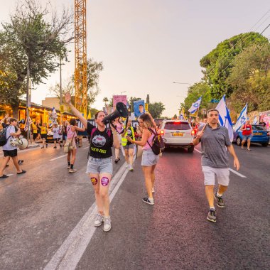 Hayfa, İsrail - 23 Ağustos 2025: Çeşitli tabelaları ve bayrakları olan insanlar, savaşın sona ermesi, rehine anlaşmasının tamamlanması ve yeni seçimler için düzenlenen protesto mitingine katıldılar. Hayfa, İsrail