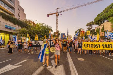 Hayfa, İsrail - 23 Ağustos 2025: Çeşitli tabelaları ve bayrakları olan insanlar, savaşın sona ermesi, rehine anlaşmasının tamamlanması ve yeni seçimler için düzenlenen protesto mitingine katıldılar. Hayfa, İsrail