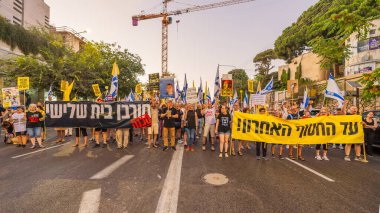 Hayfa, İsrail - 23 Ağustos 2025: Çeşitli tabelaları ve bayrakları olan insanlar, savaşın sona ermesi, rehine anlaşmasının tamamlanması ve yeni seçimler için düzenlenen protesto mitingine katıldılar. Hayfa, İsrail