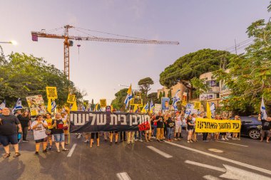 Hayfa, İsrail - 23 Ağustos 2025: Çeşitli tabelaları ve bayrakları olan insanlar, savaşın sona ermesi, rehine anlaşmasının tamamlanması ve yeni seçimler için düzenlenen protesto mitingine katıldılar. Hayfa, İsrail