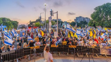 Hayfa, İsrail - 23 Ağustos 2025: Çeşitli tabela ve bayraklara sahip bir grup insan, savaşın sona ermesi, rehine anlaşmasının tamamlanması ve yeni seçimler için düzenlenen protesto mitingine katıldı. Hayfa, İsrail