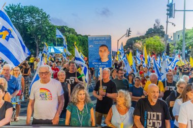 Hayfa, İsrail - 23 Ağustos 2025: Çeşitli tabela ve bayraklara sahip bir grup insan, savaşın sona ermesi, rehine anlaşmasının tamamlanması ve yeni seçimler için düzenlenen protesto mitingine katıldı. Hayfa, İsrail