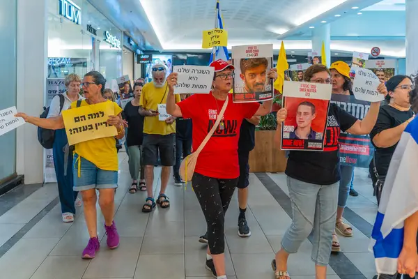 Hayfa, İsrail - 26 Ağustos 2025: Alışveriş merkezi protestosu, İsrail 'in Hayfa kentindeki Gazze Rehine Anlaşması için ülke çapında düzenlenen bir protesto gününün bir parçası olarak rehineleri destekleyen pankartlarla yürüyen insanlar