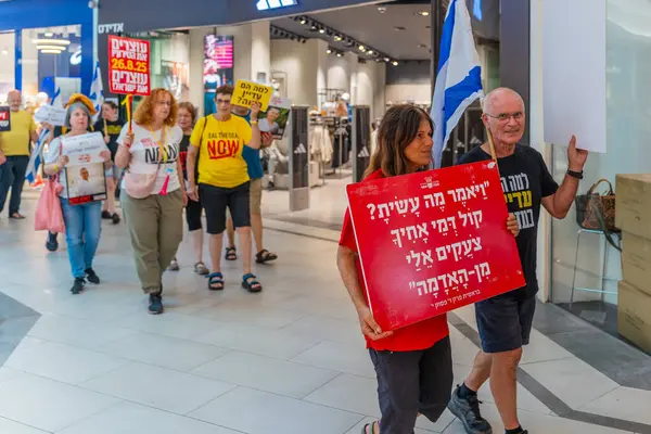 Hayfa, İsrail - 26 Ağustos 2025: Alışveriş merkezi protestosu, İsrail 'in Hayfa kentindeki Gazze Rehine Anlaşması için ülke çapında düzenlenen bir protesto gününün bir parçası olarak rehineleri destekleyen pankartlarla yürüyen insanlar