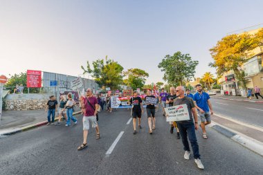 Hayfa, İsrail - 30 Ağustos 2025: İnsanlar çeşitli işaret ve bayraklarla bir protesto yürüyüşüne katılıyor, savaşın sona ermesi ve rehine anlaşmasının tamamlanması çağrısında bulunuyorlar. Hayfa, İsrail