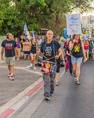 Hayfa, İsrail - 30 Ağustos 2025: Çeşitli tabela ve bayraklara sahip insanlar savaşın sona ermesi, rehine anlaşmasının tamamlanması ve yeni seçimler için düzenlenen protesto mitingine katıldılar. Hayfa, İsrail