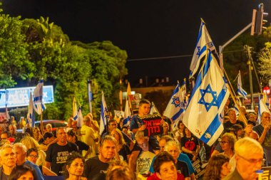 Hayfa, İsrail - 30 Ağustos 2025: Çeşitli tabela ve bayraklara sahip bir grup insan, savaşın sona ermesi, rehine anlaşmasının tamamlanması ve yeni seçimler için düzenlenen protesto mitingine katıldı. Hayfa, İsrail