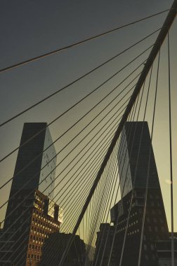 Şehrin üzerinde yükselen iki cam kulenin çarpıcı manzarası, bir köprüden görülüyor.