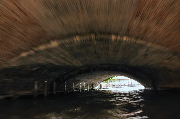 Sakin bir kanalda köprünün altından geçen bir tekneden dinamik bir çekim.