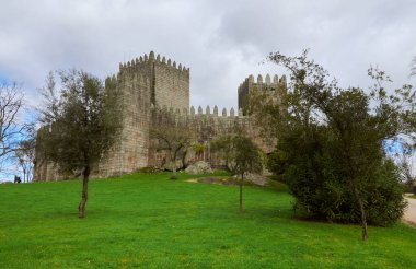 18-02-2014 Guimaraes, Portekiz - Guimares Kalesi mavi gökyüzü ve yemyeşil gökyüzünün ortasında parlak bir güneşin altında parlıyor