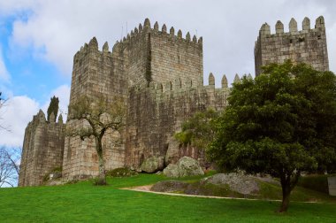 18-02-2014 Guimaraes, Portekiz - Guimares Kalesi mavi gökyüzü ve yemyeşil gökyüzünün ortasında parlak bir güneşin altında parlıyor