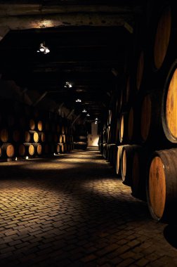 19-02-2015 Porto, Portugal - Hundreds of wooden barrels filled with Porto wine, softly illuminated in Sandeman cellars clipart