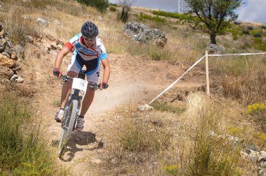 03-08-2014 Brihuega, İspanya - Bisikletçi Brihuega 'daki MTB yarışında kuru ve sıcak bir günde yokuş aşağı kayıyor