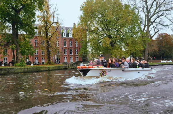 30-10-2014 Brüksel, Belçika - Bruges kanalı üzerinde geleneksel evler ve manzaralı bir parkla turist tekneleri kesişiyor