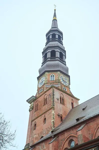 Kırmızı tuğlalar ve altın saatler sergilenen St. Catherine Kilisesi kulesinin detaylı bir yakın çekimi.