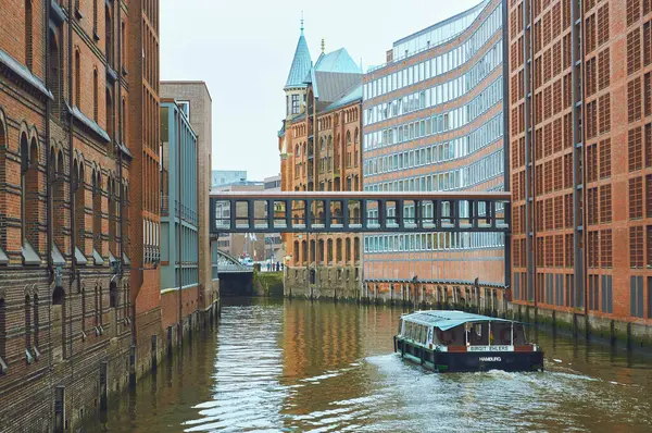 Hamburg 'un çarpıcı Speicherstadt bölgesinde tuğla binalar, kanallar, bir köprü ve bir tekne yer alıyor.