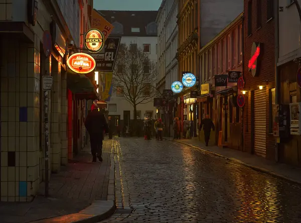 İnsanlar, Hamburg 'un St. Pauli Reeperbahn semtinin neon ışıklı caddelerinde akşam karanlığında yürürler.
