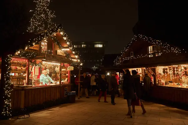 İnsanlar ışık ve tezgahlarla çevrili Hamburg 'un Noel pazarındaki şenlikli atmosferin tadını çıkarıyorlar.