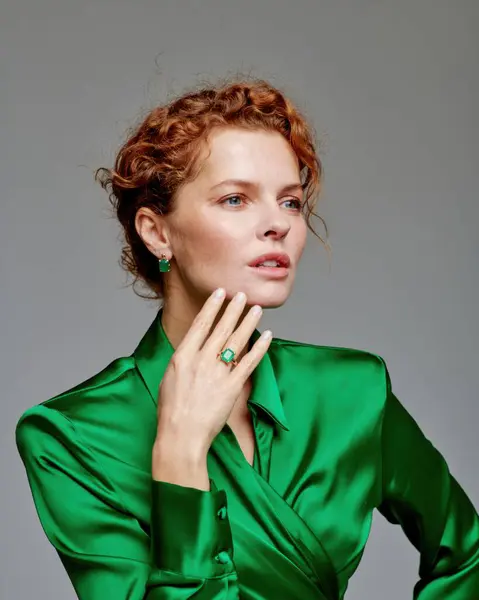 stock image A cheerful model beautifully adorned in a vibrant green satin outfit is showcasing grace and elegance