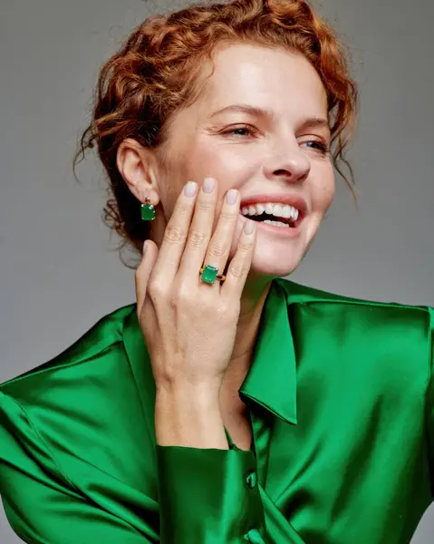 stock image A cheerful model beautifully adorned in a vibrant green satin outfit is showcasing grace and elegance