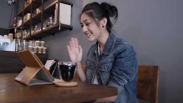 タブレットPcで優しい笑顔の若いアジアの女性の肖像画は オンラインビデオ通話放送ブロガーがカフェに座っている間 こんにちはと言う満たしています テクノロジー 接続デジタルオンラインコンセプト — ストック動画