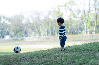 Yaz parkında futbol oynayan mutlu Asyalı çocuk. Mutlu bir çocukluk. Tatil etkinliği ve yaşam tarzı konsepti.
