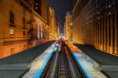 Chicago Metro trenlerinin yükseltilmiş bir noktadan görülen gece fotoğrafı.