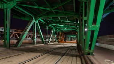 Varşova, Polonya 'da eski bir çelik köprüden geçen tramvayların zamanı. Gece çekilmiş.