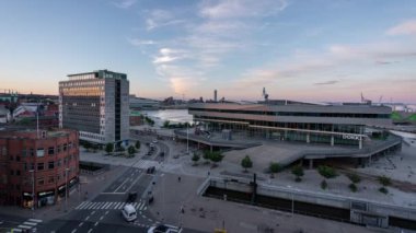 Danimarka 'da Aarhus' tan gelen gün batımında Dokk1 Kültür Evi yakınlarında arabalar ve tramvaylar var.