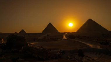 Giza 'da Mısır' daki üç piramidin (Khafre, Khufu ve Menkaure) arkasında güneş batıyor.