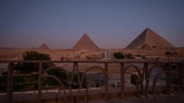 Kahire yakınlarındaki Giza 'daki 3 ünlü piramidin gündoğumunun zamanı. Yakınlardaki bir otelin çitlerinden kaçırılmış.