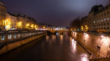 Paris, Fransa 'daki Saint Michel Köprüsü yakınlarındaki Seine nehrinin kıyısındaki binaların gece gündüz süreleri doluyor.