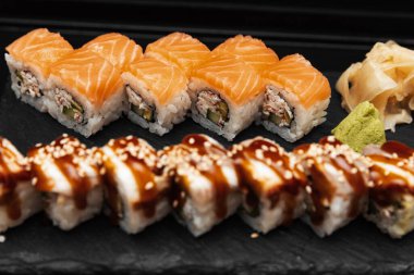 Siyah arka planı olan taştan bir tabakta suşi.