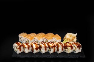 Siyah arka planı olan taştan bir tabakta suşi.