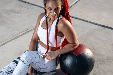 Close up. Resting. Athletic woman doing exercise with med ball. 