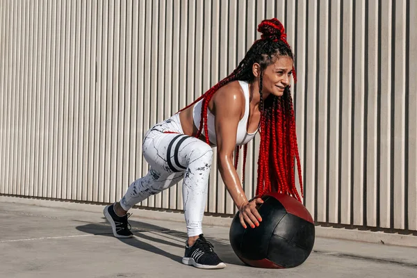 Athletic woman doing exercise change of legs with med ball. Stre