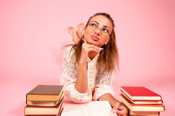 Розовый фон, девушка читает книги, книжный любовник, студент лежит на полу среди большого количества книг