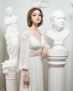 Beyaz bir heykelin önünde bir gelin duruyor..