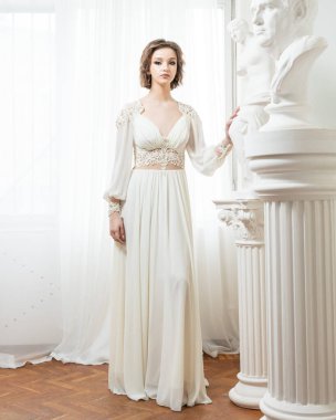 Beyaz bir heykelin önünde bir gelin duruyor..