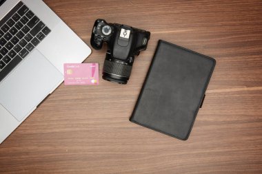 Ahşap bir masada bir laptop ve bir kamera.