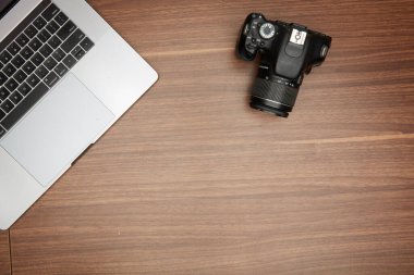 Ahşap bir masada bir laptop ve bir kamera.