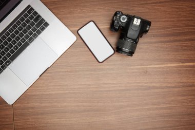 Ahşap bir masada bir laptop ve bir kamera.