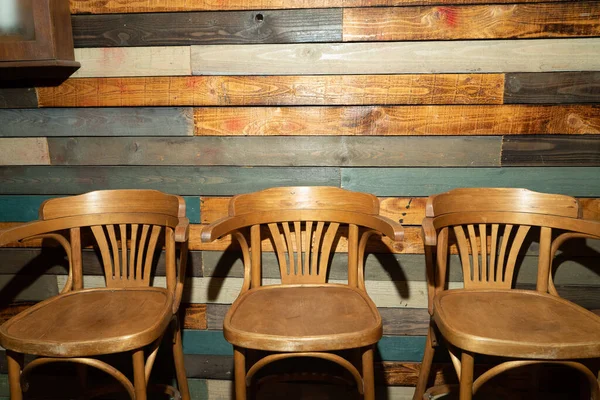 Duvara yaslanmış üç tahta sandalye.