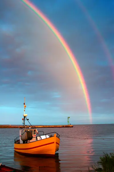 Colorful rainbow by the water, view of the boat and a calm bay