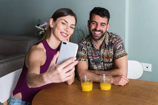 Relaxed young interracial couple or friends say hi and talking in video conference by mobile phone together in living room at home, Happy young man and woman with smartphone