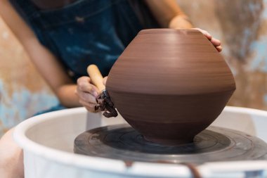 Kadın el çömlekçisi atölyesinde otururken çömlek tekeri üzerinde çalışıyor.