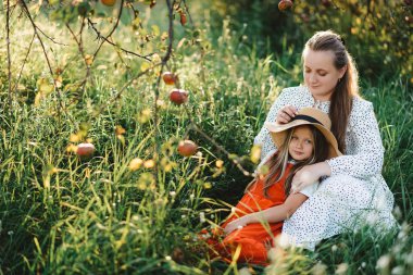 Bir anne yaz bahçesinde çocuklarının kafasını okşuyor.